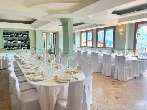 um grande salão de banquetes com mesas brancas e cadeiras brancas em Hotel Miranda em Riva di Solto