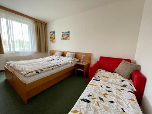 a bedroom with two beds and a red chair at U Zámečku 108 in Kyjov