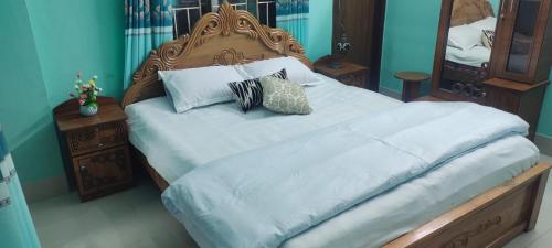 a bedroom with a large bed with white sheets and pillows at Zuned Homes Sylhet in Sylhet