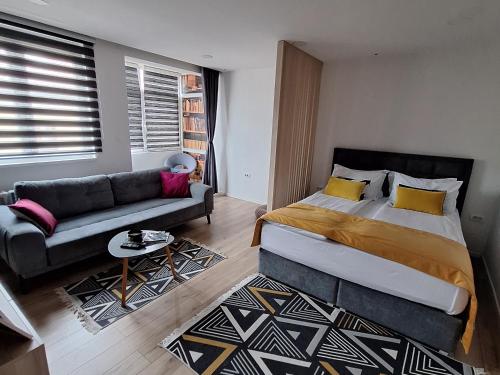 a bedroom with a large bed and a couch at Apartman Orhideja with Free Parking in Sarajevo