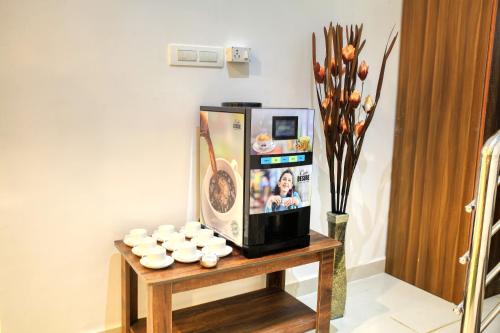 a room with a tv on a table with cups at HOTEL VISA INN NEAR KEMPEGOWDA AIRPORT in Bengaluru
