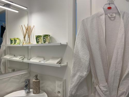 La salle de bains est pourvue d'un peignoir blanc suspendu à côté d'un lavabo. dans l'établissement Havre de paix, à Coulaines