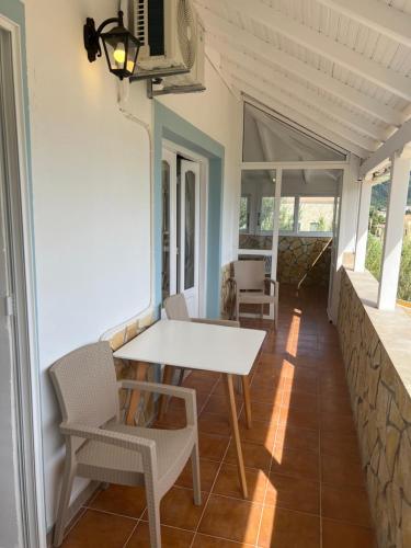 a porch with a white table and chairs at Hamre Apartments (Nicholas) in Agios Georgios Pagon