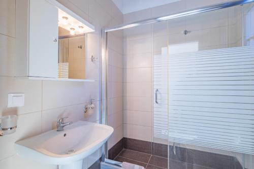 a white bathroom with a sink and a shower at Sundy Maria Apartments in Stoupa