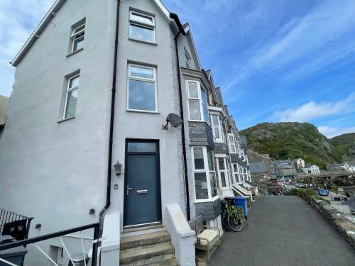 a white house with a blue door on a street at Harbour House in Barmouth