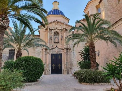 a church with palm trees in front of it at Ruim appartement tot 6 personen in Monóvar