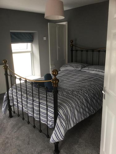 a bedroom with a bed with a striped comforter and a window at Harbour House in Barmouth