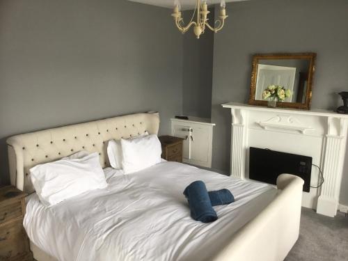 a bedroom with a white bed with a fireplace at Harbour House in Barmouth