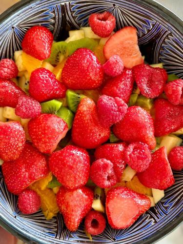 a bowl of fruit with strawberries and kiwis at La Maison de Jade & Spa in La Roche-de-Glun