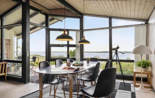 a dining room with a table and chairs and large windows at Amazing Home In Aabenraa With Kitchen in Aabenraa