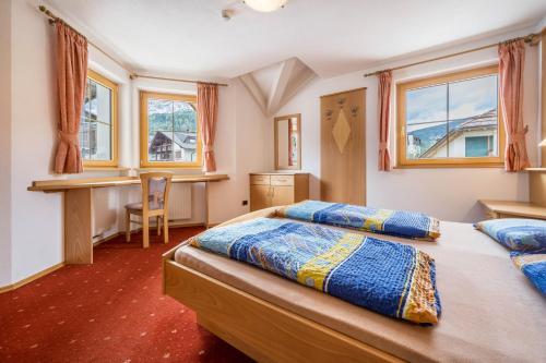 1 dormitorio con 2 camas, escritorio y ventanas en Residence Oberhauser Apt 4 en Valdaora di Sopra