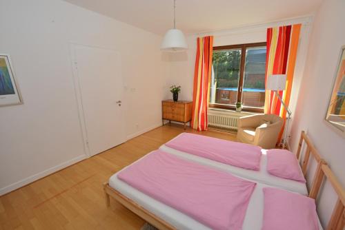 Moderne Ferienwohnung Deichstrasse في هيننف: غرفة نوم بسرير وردي ونافذة