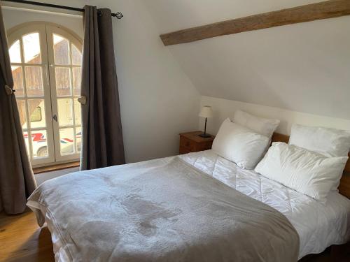 une chambre avec un grand lit blanc avec une fenêtre dans l'établissement LE COTTAGE 72 - Les contensières, à Saint-Vincent-du-Lorouër