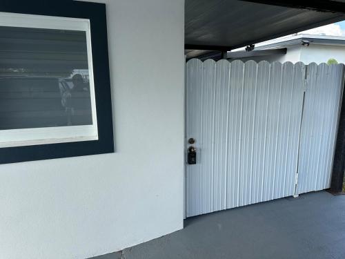 a white fence next to a white wall with a picture at Adrien Guest Studio in Miami Gardens