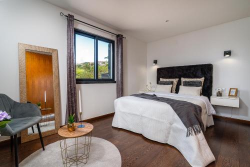 a white bedroom with a large bed and a window at Melblue in Estreito da Calheta