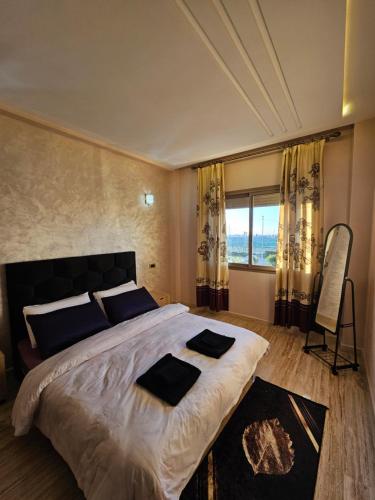 - une chambre avec un grand lit et une grande fenêtre dans l'établissement MIA Appartement - résidence les champs du printemps, à Casablanca