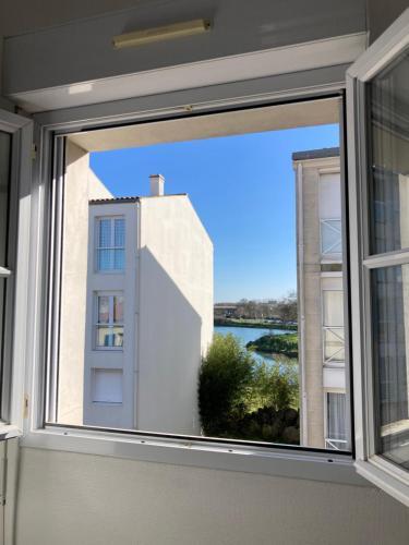 une fenêtre avec vue sur un bâtiment dans l'établissement Lotentik residence, à La Rochelle