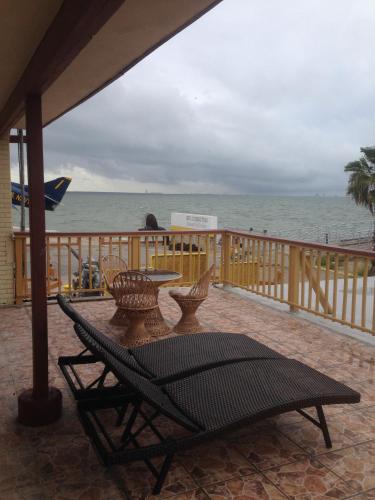 a patio with a table and chairs and the ocean at Capri Beach Hotel in Corpus Christi