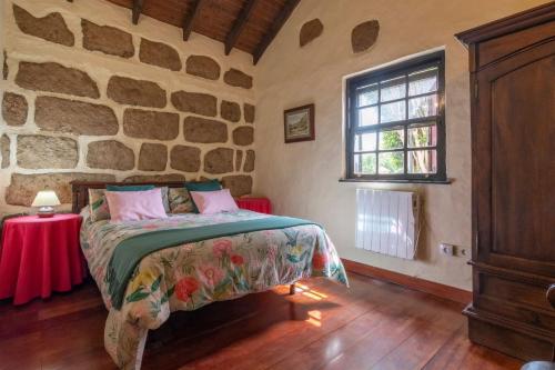 a bedroom with a bed and a stone wall at Casa Rural Mi Perlita in Vega de San Mateo