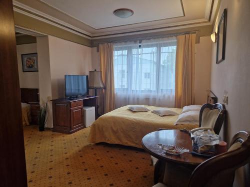 une chambre d'hôtel avec un lit, une table et une télévision dans l'établissement Crama Haiducilor, à Cluj-Napoca
