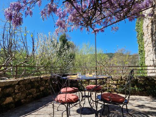 una mesa y sillas sentadas bajo un árbol con flores en La Fontaine d'Aubrac, en Florentin-la-Capelle