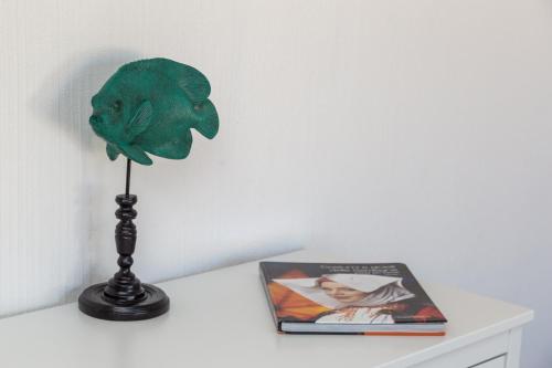 a green fish on a table next to a book at Sa Dommu e Mare in Santa Maria Navarrese