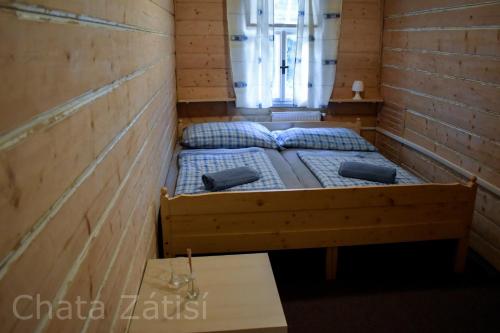 a small room with a bed with blue pillows at Penzion chalupa Lesní zátiší in Harrachov