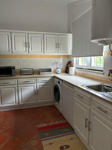 a kitchen with white cabinets and a washing machine at Casa da Nogueira in Tomar