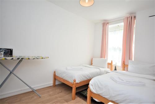 a bedroom with two beds and a window at Lovely 3 Bedroom Apartment in Standford Hill in London