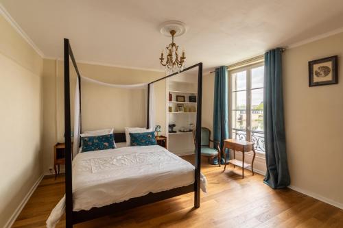 a bedroom with a four poster bed with a chandelier at Villa du Loir in La Flèche
