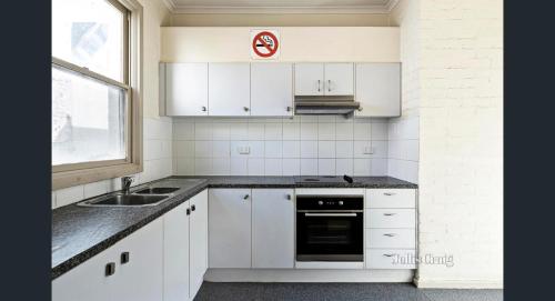 a kitchen with white cabinets and a sink and a window at Ausis Accommodation Services in Melbourne