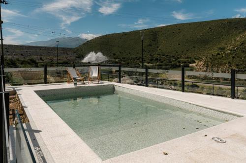 uma piscina com duas cadeiras sentadas em cima em Hostería La Angostura em Tafí del Valle