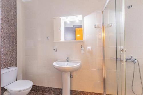 a bathroom with a toilet and a sink and a shower at Sundy Maria Apartments in Stoupa