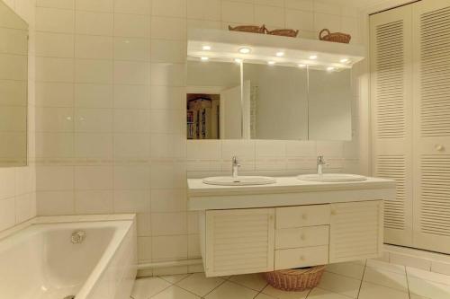 une salle de bain avec deux lavabos, une baignoire et un miroir dans l'établissement LE Saint Martin, à Versailles