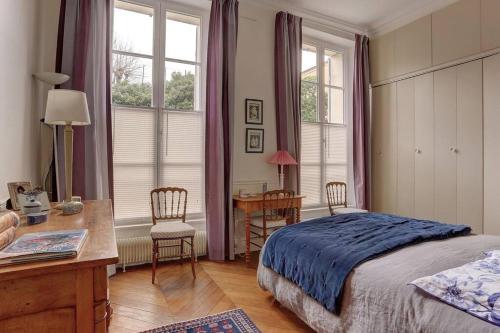 une chambre avec un lit, un bureau et des fenêtres dans l'établissement LE Saint Martin, à Versailles