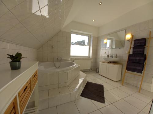 a white bathroom with a tub and a sink at Luhe Idyll in Luhdorf