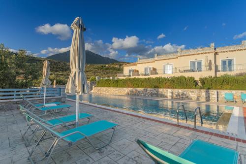 a pool with chairs and an umbrella next to a building at Sundy Maria Apartments in Stoupa