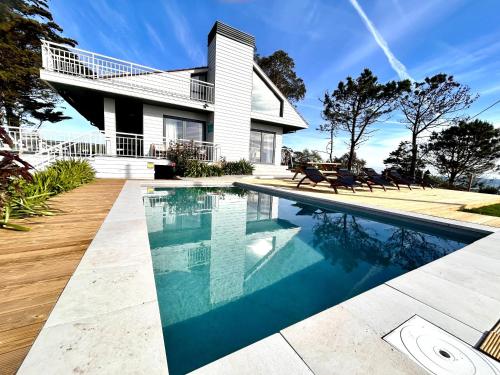 uma casa com piscina em frente a uma casa em Espectacular Villa con acceso privado a la playa de Oyambre em San Vicente de la Barquera