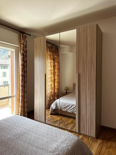 sypialnia z lustrem, łóżkiem i oknem w obiekcie Apartment in town centre and nearby the lake w mieście Riva del Garda