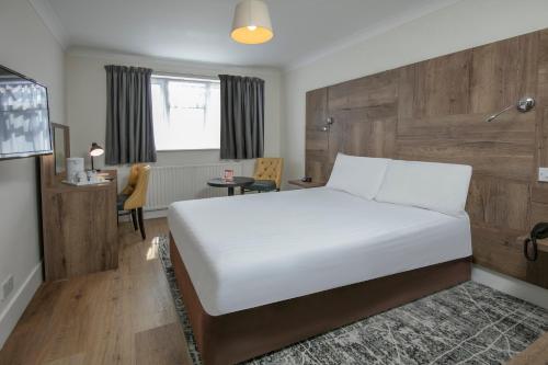 een slaapkamer met een wit bed en een tafel bij Best Western White House Hotel in Watford