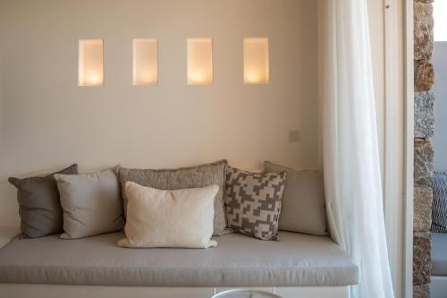 a couch with pillows and lights on a wall at Nomia Sunset Suites Mykonos in Tagou