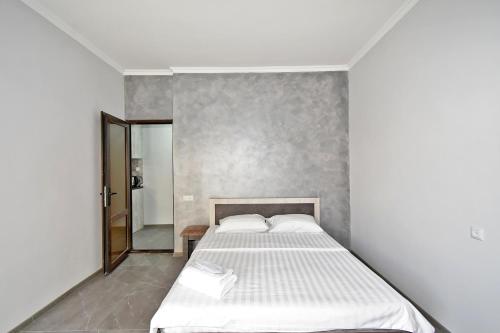 Schlafzimmer mit einem weißen Bett und einem Spiegel in der Unterkunft Sirik in Yerevan