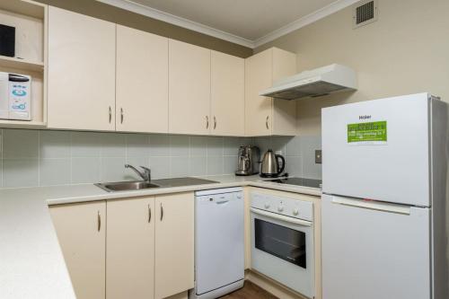 a kitchen with white cabinets and a white refrigerator at Methven Nest Apartment in Methven