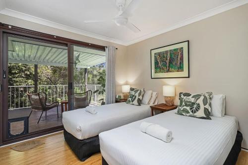 two beds in a room with a balcony at Riverfront Oasis in Elanora in Gold Coast