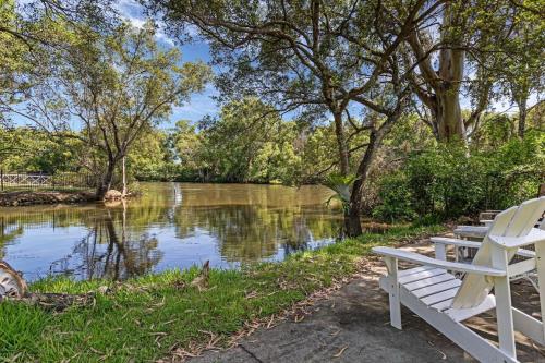 a white bench sitting next to a river at Riverfront Oasis in Elanora in Gold Coast