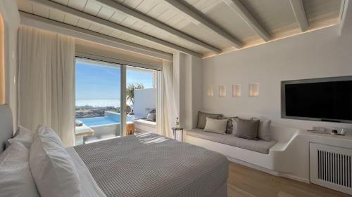Nomia Sunset Suites Mykonos في Tagou: غرفة نوم بسرير وتلفزيون وأريكة
