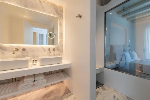 a bathroom with two sinks and a large mirror at Nomia Sunset Suites Mykonos in Tagou