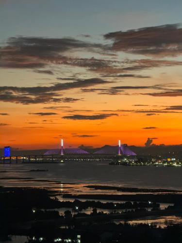 an orange sunset with a bridge in the distance at Condo Hotel near Mactan Cebu Airport in Mactan