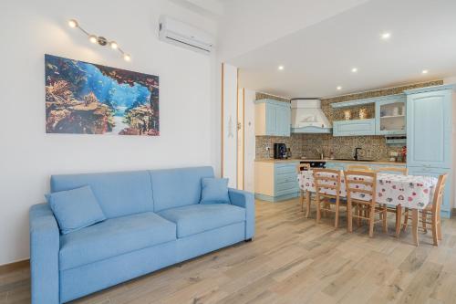a living room with a blue couch and a kitchen at Casa Iole Portopalo in Portopalo
