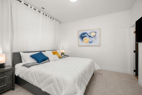 een slaapkamer met een bed met witte lakens en blauwe kussens bij Updated Family Friendly Hillyard Gem NEW HOT TUB! in Spokane